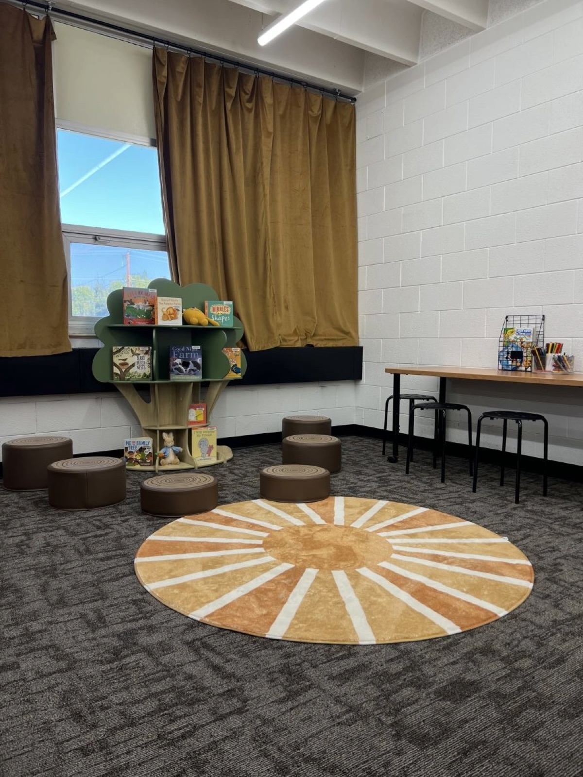 Children's reading corner with a tree-shaped bookshelf and stools