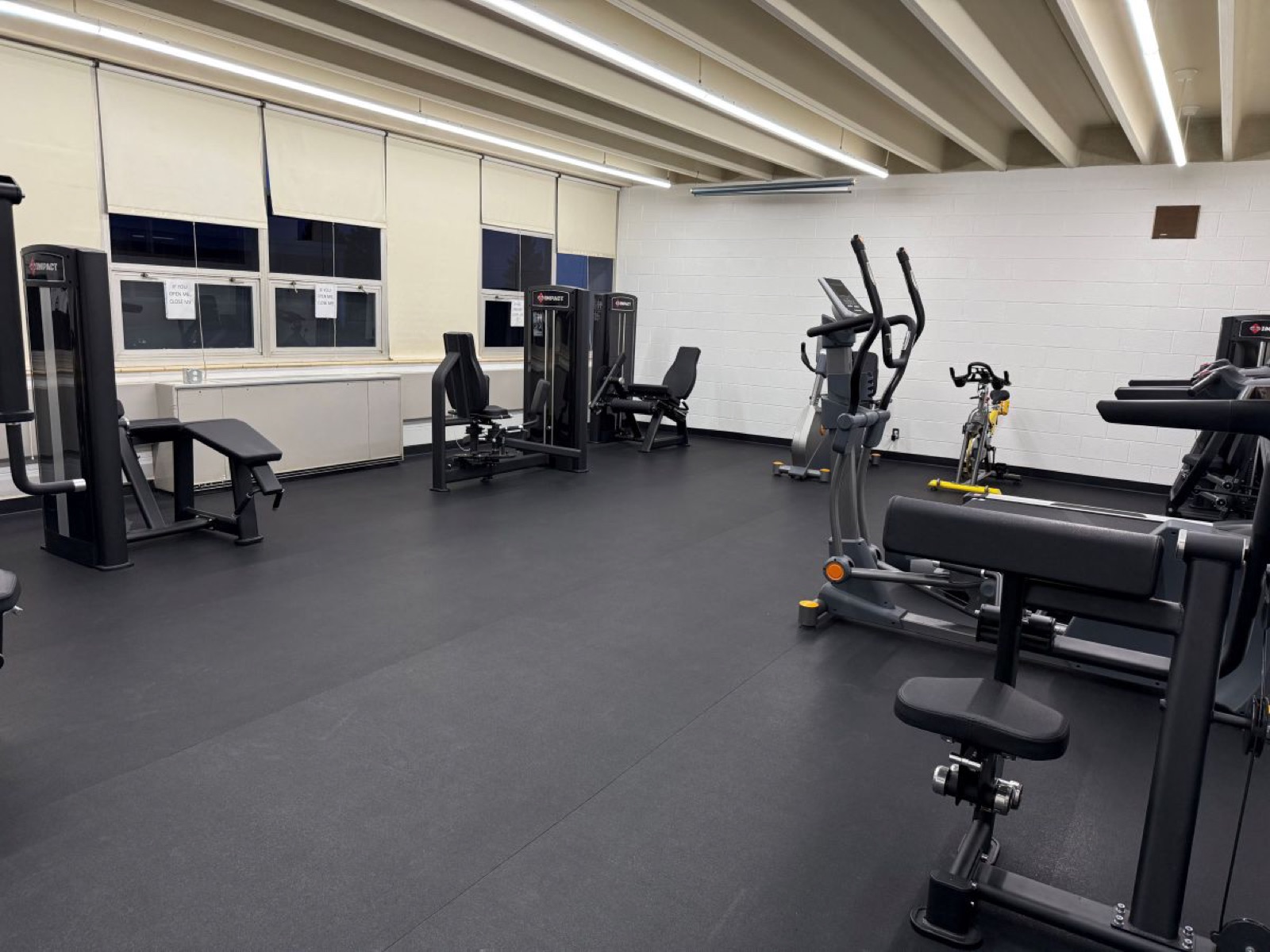 Weight machines, an elliptical and a spin bike along the windows of the fitness center