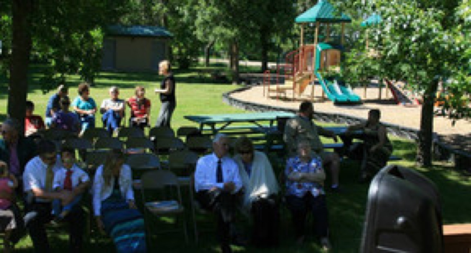 Community gathering under the trees at a Halliday park